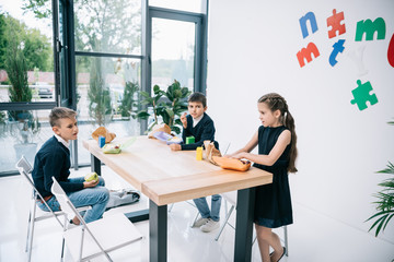 Wall Mural - Cute little classmates eating lunch at break in school