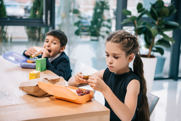 Wall Mural - Cute little classmates eating lunch at break in school
