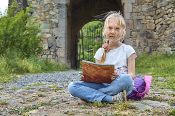 little girl with face stained with paint drawing outdoors