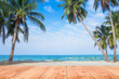 © Sunday Stock - Wooden table in front of abstract blurred sea & coconut tree background. For present your products. Summer Concept