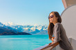 Luxury travel Alaska cruise holiday woman relaxing on balcony looking at view of mountains and nature landscape. Asian girl sunglasses tourist.