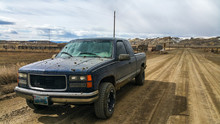 Older Chevy Silverado GMC Sierra Pickup Truck K1500 Off Road In Country Side Of Wyoming While Covered In Mud