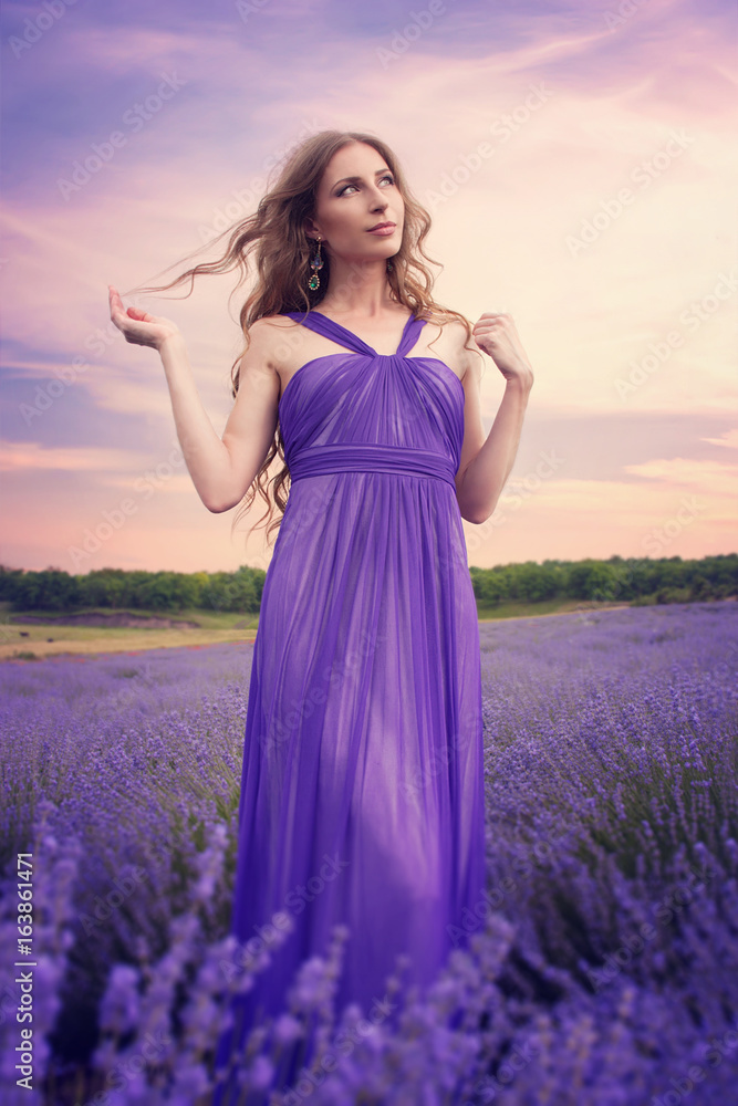 blonde hair purple dress Young woman with blonde hair wearing a purple dress and high heels,  standing and posing Stock Photo