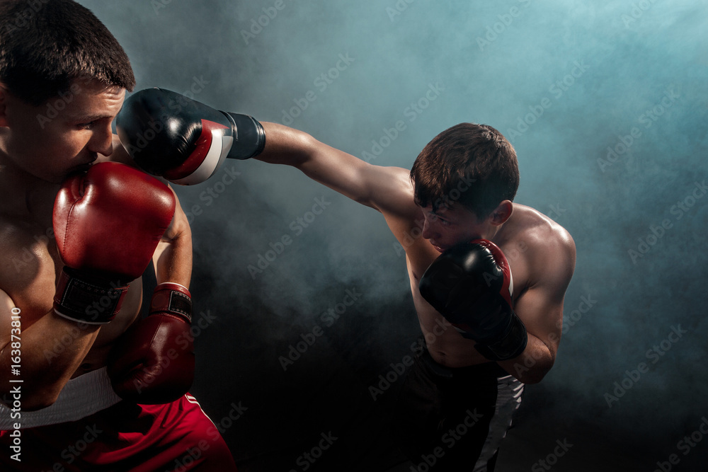 Two professional boxer boxing on black smoky background,