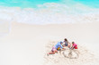 © travnikovstudio - Father and little daughters making sand castle at tropical beach