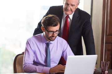 Puzzled businessmen looking at laptop screen