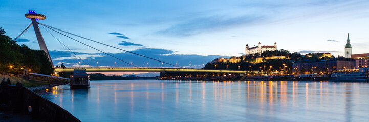 Bratislava, New Bridge, Castle, Cathedral during dusk from a boat on river Danube, panorama 3:1