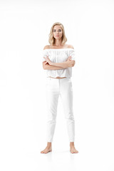 Wall Mural - Beautiful serious blond woman in white blouse and pants on white background