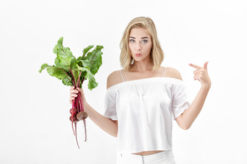 Sticker - Beautiful blond woman is pointing at beetroot with green leaves on white background. Health and vitamins