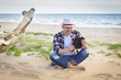 © elinque - A man in smart casual hipster style with tablet combining work with relax on the beach of Baltic Sea
