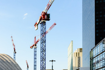 Four tower cranes on a construction site in the middle of a business district in full development.