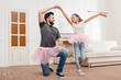 © LIGHTFIELD STUDIOS - multicultural father and daughter in pink tutu tulle skirts dancing at home