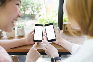 Two young asian woman using smart phone together on hand with blank screen copy space for add picture or text.