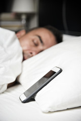 Wall Mural - young man in bed close to his smartphone