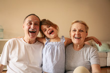 Playful Grandparents With Their Granddaughter.