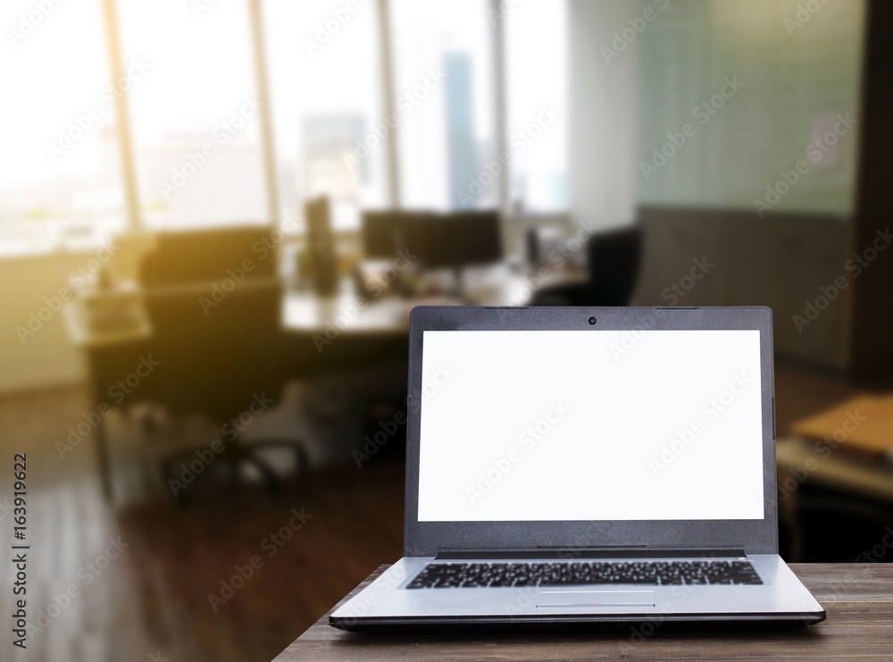 Laptop computer with white blank screen on wooden table with blurred ...