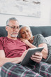 © LIGHTFIELD STUDIOS - smiling senior couple with digital tablet resting in bed together