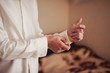 © ViDi Studio - The groom fastens the cufflink on the shirt sleeve close-up