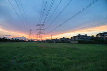 Wall Mural - Group silhouette transmission towers (steel lattice/power tower, electricity pylon) next to apartment complex at sunset in US. Texture high voltage pillar, overhead power line, industrial background.