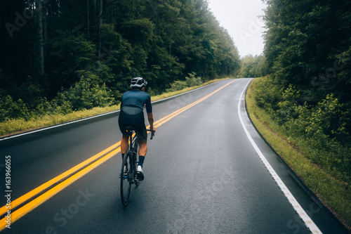 Cuadros en Lienzo Selective focus shot of professional road cyclist riding down wet and windy moun