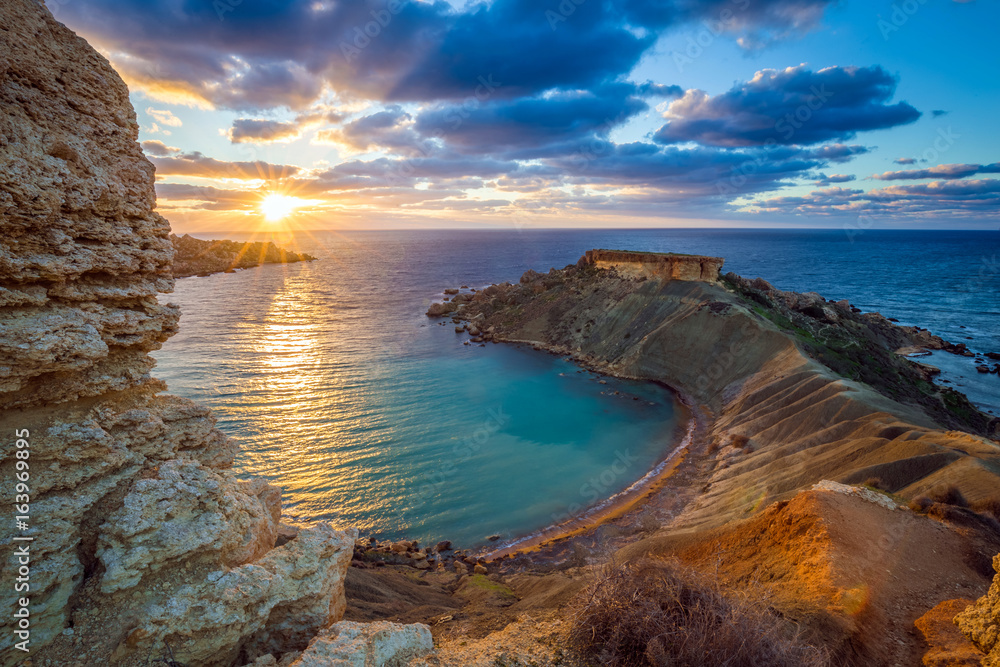 Mgarr, Malta - Panorama of Gnejna bay, the most beautiful beach in Malta at sunset with beautiful colorful sky and golden rocks taken from Ta Lippija - obrazy, fototapety, plakaty 