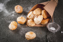 Homemade Baking, Puff Pastries. Trendy Food. Cronuts Popcorn, Puff Donuts Holes, In Paper Bag, With Powdered Sugar. On A Dark Stone Table. Copy Space