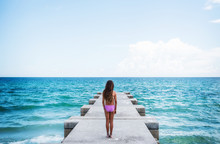 Girl Standing On Pier Looking At Ocean