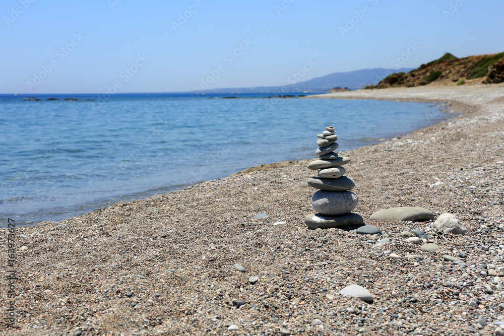 Stos płaskich kamieni na kamienistej plaży, Rodos, Grecja. - obrazy, fototapety, plakaty 