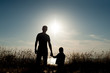 © ruslanshug - Silhouette of adult man and little boy against the backdrop of the sea sunset