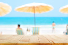 Wood Table Top On Blurred Blue Sea And White Sand Beach Background With Some People