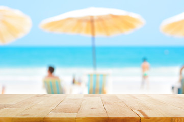 Wood table top on blurred blue sea and white sand beach background with some people