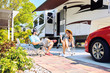 Young couple sits on chairs near camping trailer and car