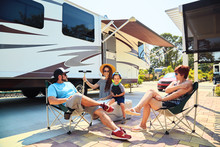 Mother,father,son And Grandmother Sitting Near Camping Trailer,smiling.Woman,men,kid Relaxing On Chairs Near Car.Family Spending Time Together On Vacation Near Sea Or Ocean In Modern Rv Park