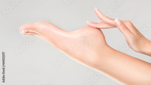 Zdjęcie XXL Idealne czyste kobiece stopy i pięta. Piękna kobieca ręka dotyka jej zadbane stopy. Pielęgnacja zdroju, peelingu i stóp.