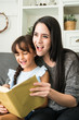 © Success Media - young mother reading a book to her daughter at home