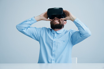 A young guy with a beard on a light background in virtual reality glasses