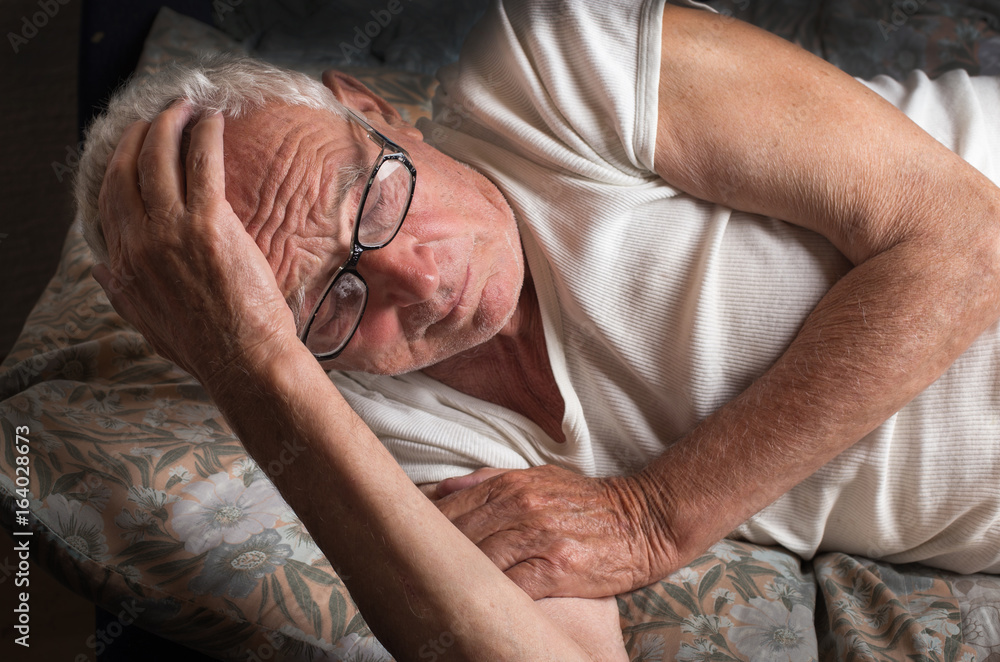 Old man lying in bed Stock Photo | Adobe Stock