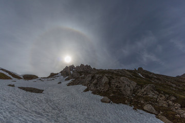 natural halo with sun in blue sky and snowy mountains