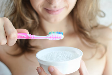 Young pretty girl brushing her tooth with a toothbrush with tooth powder. Teeth Whitening.
