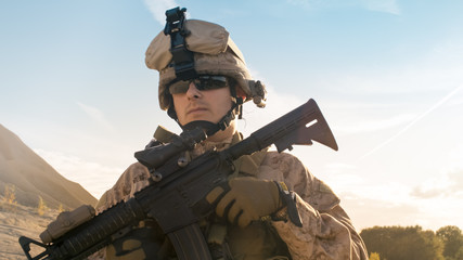 Wall Mural - Portrait of Fully Equipped Solder Holding Assault Rifle and Standing in the Desert Environment.