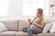 © Prostock-studio - Pregnant woman with glass of water sitting on sofa
