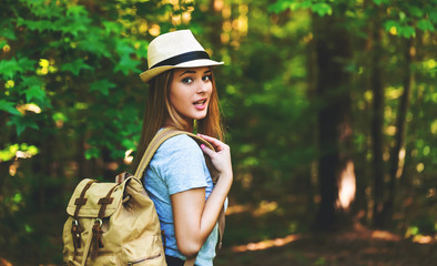 Young woman in the forest with a backpack and hat