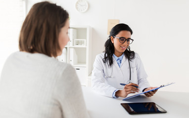 Wall Mural - doctor with clipboard and woman patient at clinic