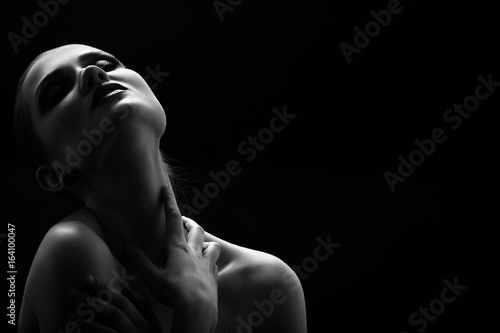 Fotografía Black and white shot of woman posing sensually holding head up on black backgrou