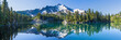 Leinwandbild Motiv Volcanic mountain in morning light reflected in calm waters of lake.