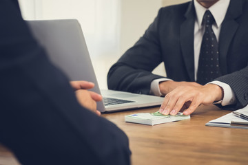 Businessman giving money, Euro banknotes, to his partner on working desk