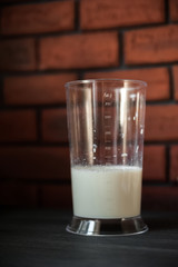 The process of preparation in detail. Cooking, kneading dough. A glass of milk, 2 eggs, a saucer with flour and a blue napkin on a black wooden table