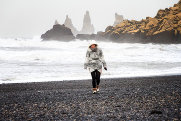 Wall Mural - Beautiful woman on the black beach of Vik, Iceland, on a stormy winter day