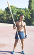 © Addoro - Closeup of a handsome middle-aged man working out on a running track. Healthy adult man holding the wooden barbell. Tanned skin and shirtless middle-aged man exercising.