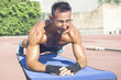 © Addoro - Handsome middle aged man working out on a running track. Healthy adult man doing plank exercise. Tanned skin and shirtless middle-aged man.